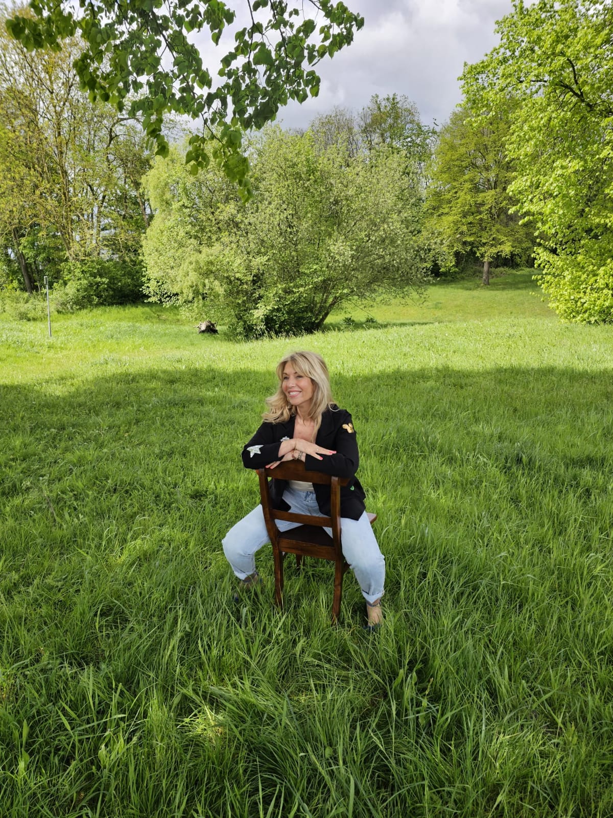 Pascale, de relatiecoach, zittend op een stoel op een grasveld